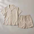 one beige men's two-piece set consisting of a short-sleeve button-front camp-collar resort shirt and matching drawstring shorts arranged side by side, both fully visible